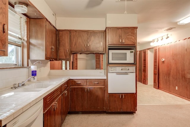 2502 Greenlawn Pkwy, Austin, TX 78757 - kitchen with white appliances, tile countertops, a sink, light carpet, and brown cabinetry