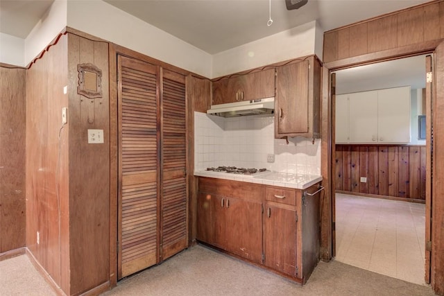 2502 Greenlawn Pkwy, Austin, TX 78757 - kitchen with under cabinet range hood, tile countertops, white gas stovetop, wood walls, and backsplash