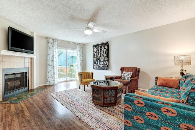 2008 Kenneth Ave Unit B, Austin, TX 78741 - living area featuring a tiled fireplace, wood finished floors, a ceiling fan, a textured ceiling, and baseboards