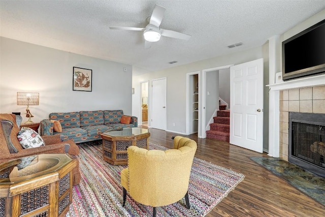 2008 Kenneth Ave Unit B, Austin, TX 78741 - living room featuring stairway, wood finished floors, a textured ceiling, a tile fireplace, and a ceiling fan