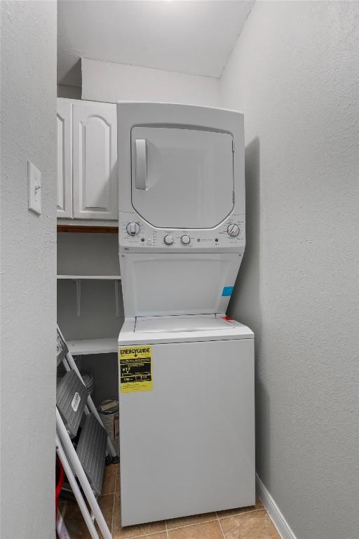 203 E 31st St Unit 304, Austin, TX 78705 - washroom with stacked washing machine and dryer, light tile patterned floors, cabinet space, and baseboards