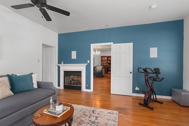 1922 W Lake Dr, Taylor, TX 76574 - living room featuring wood finished floors, a ceiling fan, a chandelier, and a fireplace