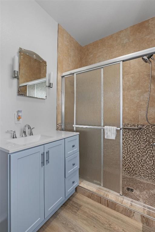 1922 W Lake Dr, Taylor, TX 76574 - bathroom featuring a stall shower, vanity, and wood finished floors