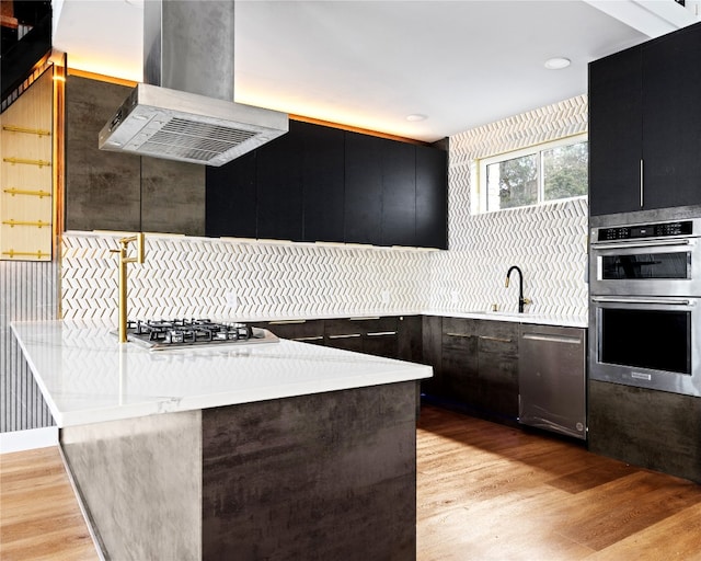 1800 Buffalo Gap Rd, Austin, TX 78734 - kitchen with island range hood, appliances with stainless steel finishes, dark cabinets, light wood-type flooring, and light countertops