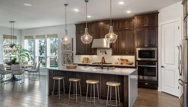 1316 Novara Trl, Leander, TX 78641 - kitchen with stainless steel appliances, under cabinet range hood, decorative backsplash, a kitchen bar, and recessed lighting