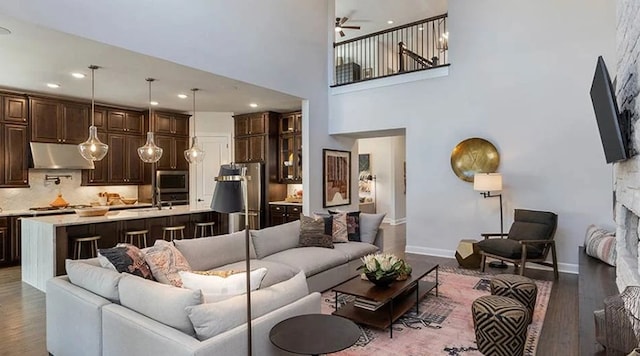 1316 Novara Trl, Leander, TX 78641 - living room with ceiling fan, wood finished floors, a towering ceiling, a stone fireplace, and recessed lighting