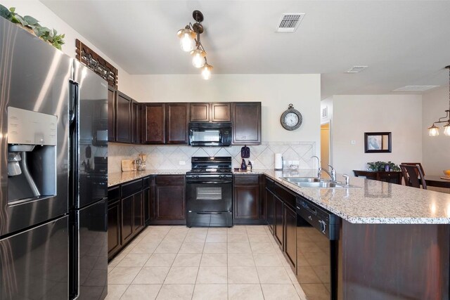 1407 Brashear Ct, Cedar Park, TX 78613 - kitchen with black appliances, a peninsula, backsplash, light tile patterned floors, and dark brown cabinetry