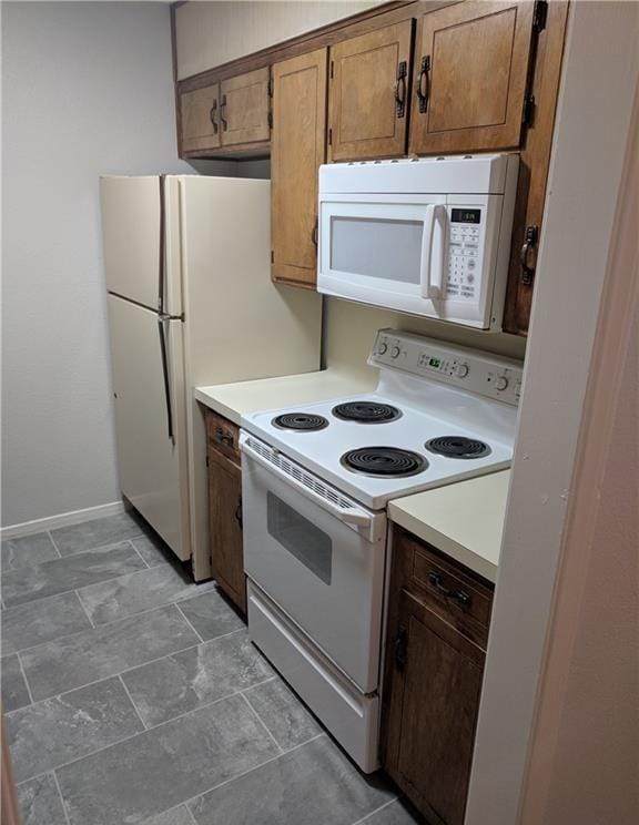 1002 Charisse St, Killeen, TX 76543 - kitchen with white appliances, light countertops, baseboards, and brown cabinets