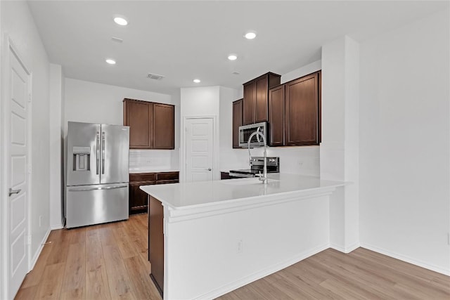 13308 Nancy Reagan St, Manor, TX 78653 - kitchen featuring appliances with stainless steel finishes, light wood-style floors, dark brown cabinets, light countertops, and recessed lighting