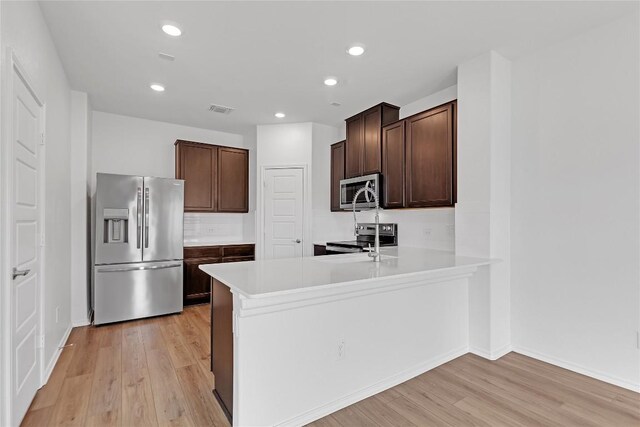 13308 Nancy Reagan St, Manor, TX 78653 - kitchen featuring stainless steel appliances, light wood finished floors, dark brown cabinets, light countertops, and recessed lighting