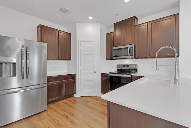 13308 Nancy Reagan St, Manor, TX 78653 - kitchen featuring stainless steel appliances, light wood finished floors, tasteful backsplash, light countertops, and recessed lighting