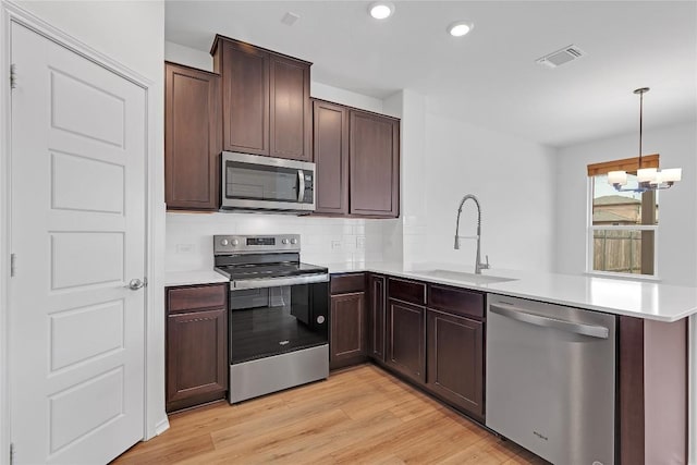 13308 Nancy Reagan St, Manor, TX 78653 - kitchen featuring appliances with stainless steel finishes, a peninsula, backsplash, light countertops, and a chandelier
