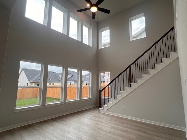 20013 Aqua Reef Dr, Austin, TX 78747 - unfurnished living room featuring wood finished floors, a high ceiling, a ceiling fan, and stairway