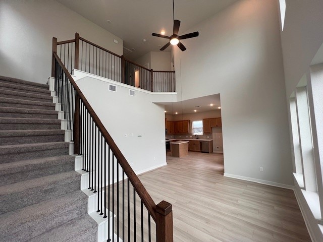 20013 Aqua Reef Dr, Austin, TX 78747 - staircase featuring wood finished floors, a ceiling fan, and a towering ceiling