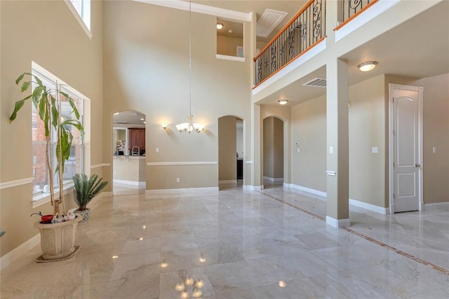 222 Vailco Ln, Austin, TX 78738 - unfurnished living room with arched walkways, light marble finish floors, a chandelier, and a high ceiling