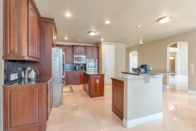 222 Vailco Ln, Austin, TX 78738 - kitchen featuring stainless steel appliances, an island with sink, arched walkways, backsplash, and recessed lighting