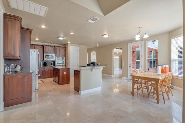 222 Vailco Ln, Austin, TX 78738 - kitchen featuring appliances with stainless steel finishes, a center island with sink, arched walkways, a chandelier, and recessed lighting