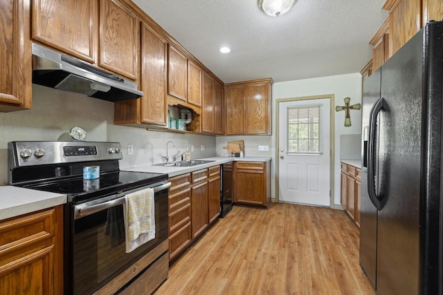 1201 County Road 229, Florence, TX 76527 - kitchen with black appliances, light wood finished floors, brown cabinets, under cabinet range hood, and light countertops
