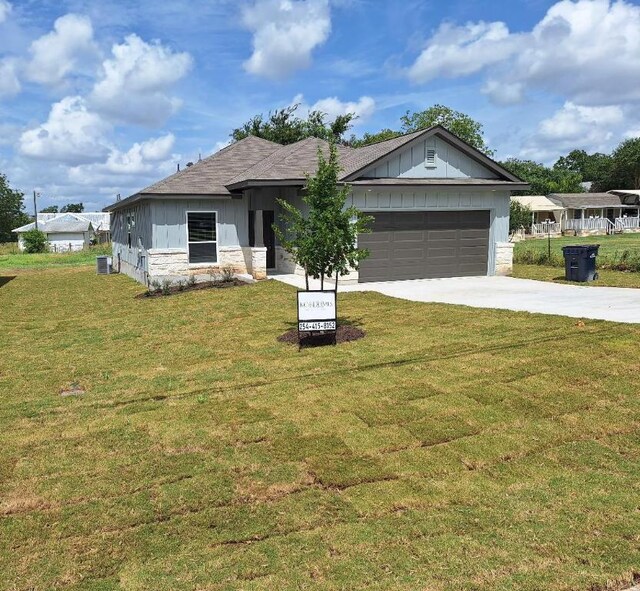504 S Story Sts, Florence, TX 76527 - view of front of house featuring concrete driveway, an attached garage, stone siding, board and batten siding, and a front yard