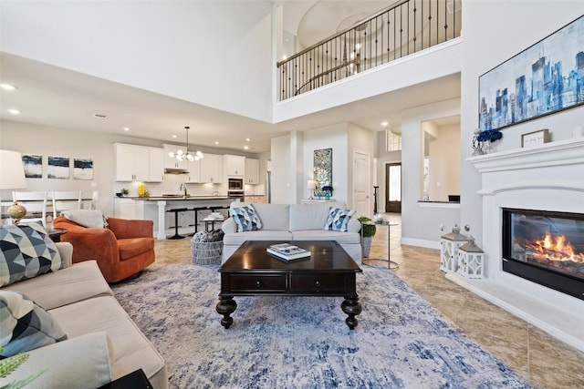 4225 Borho Ranch St, Leander, TX 78641 - living room with a towering ceiling, recessed lighting, a chandelier, a glass covered fireplace, and light tile patterned floors