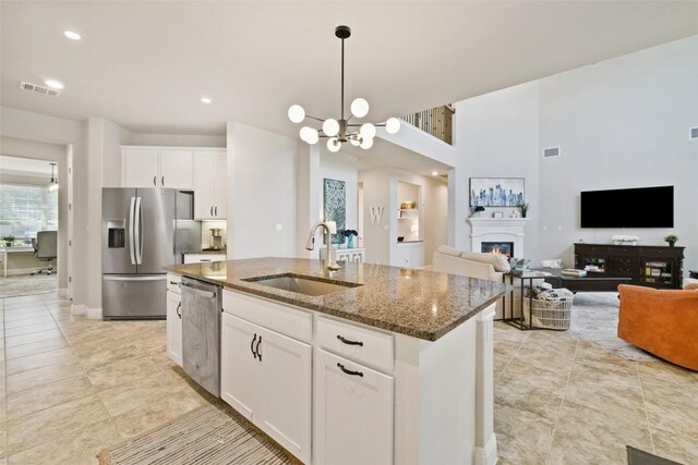 4225 Borho Ranch St, Leander, TX 78641 - kitchen with stainless steel appliances, dark stone counters, a kitchen island with sink, decorative light fixtures, and white cabinetry
