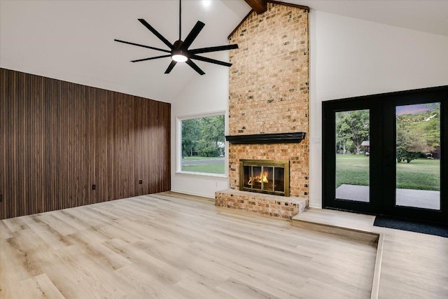 503 Elm St, Bastrop, TX 78602 - unfurnished living room featuring high vaulted ceiling, wood finished floors, a ceiling fan, beam ceiling, and a brick fireplace
