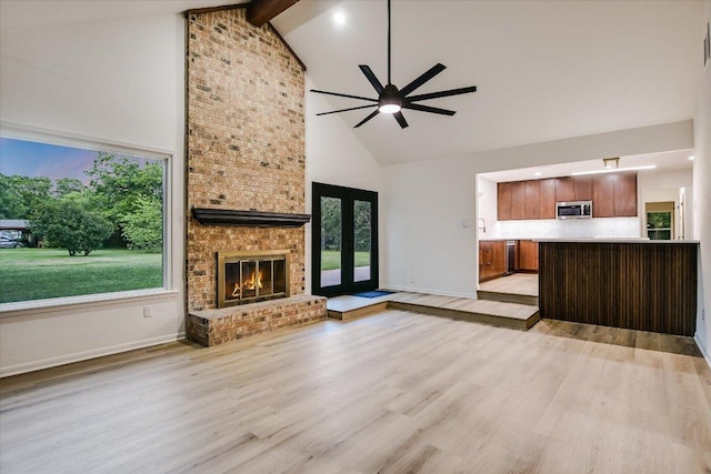 503 Elm St, Bastrop, TX 78602 - unfurnished living room with high vaulted ceiling, ceiling fan, a fireplace, light wood-style floors, and beamed ceiling
