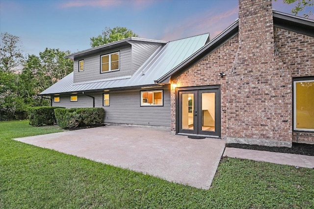 503 Elm St, Bastrop, TX 78602 - back of house featuring a yard, a patio area, a metal roof, and a chimney