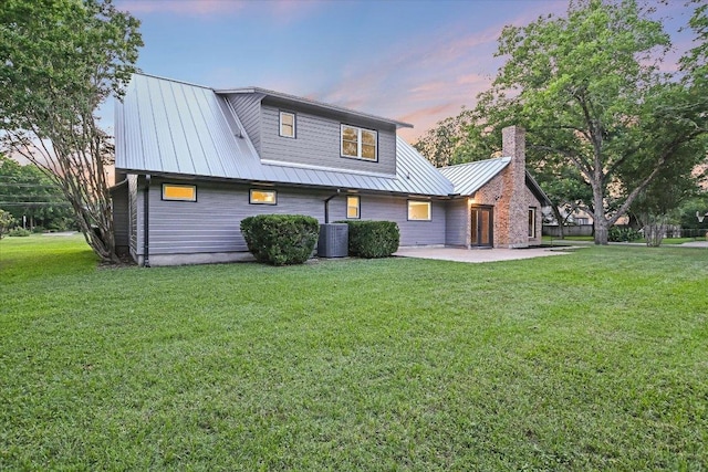 503 Elm St, Bastrop, TX 78602 - rear view of property featuring a lawn, a patio, a chimney, and a metal roof