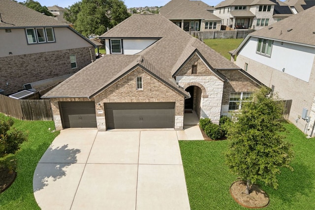 1816 Arapaho Mountain Pass, Leander, TX 78641 - view of front facade featuring concrete driveway, stone siding, a residential view, a garage, and a shingled roof