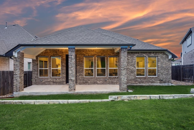 1816 Arapaho Mountain Pass, Leander, TX 78641 - back of property at dusk featuring brick siding, a patio area, and a shingled roof