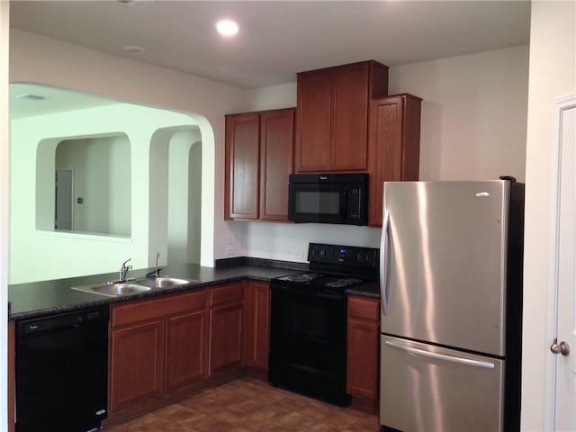 13701 Abraham Lincoln St, Manor, TX 78653 - kitchen with black appliances, dark countertops, arched walkways, brown cabinets, and recessed lighting