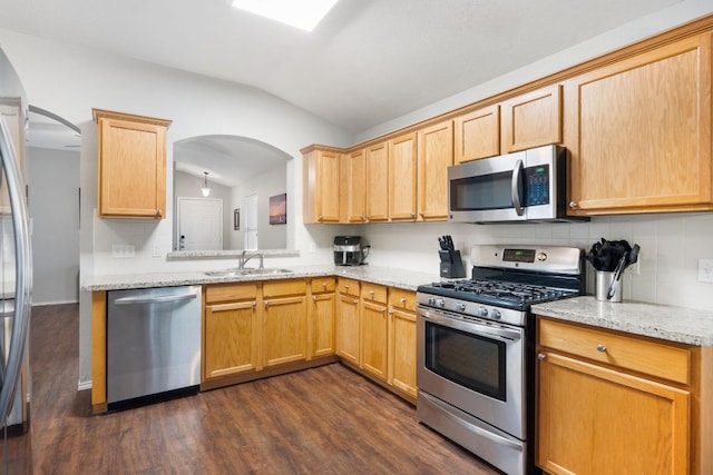 1109 Pine Portage Loop, Leander, TX 78641 - kitchen featuring appliances with stainless steel finishes, vaulted ceiling, arched walkways, dark wood-style floors, and light stone counters