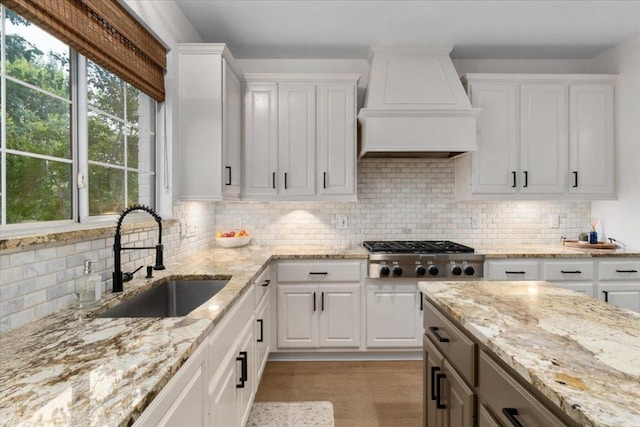 5304 China Garden Dr, Austin, TX 78730 - kitchen with premium range hood, stainless steel gas cooktop, white cabinetry, and decorative backsplash