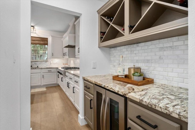 5304 China Garden Dr, Austin, TX 78730 - kitchen featuring beverage cooler, stainless steel gas cooktop, backsplash, light stone countertops, and white cabinets