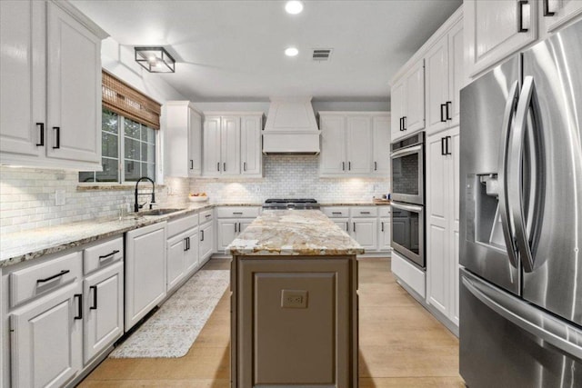 5304 China Garden Dr, Austin, TX 78730 - kitchen featuring appliances with stainless steel finishes, premium range hood, white cabinets, decorative backsplash, and recessed lighting
