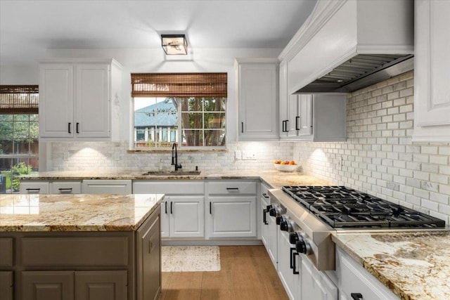 5304 China Garden Dr, Austin, TX 78730 - kitchen featuring custom range hood, stainless steel gas stovetop, light wood-style floors, white cabinetry, and healthy amount of natural light