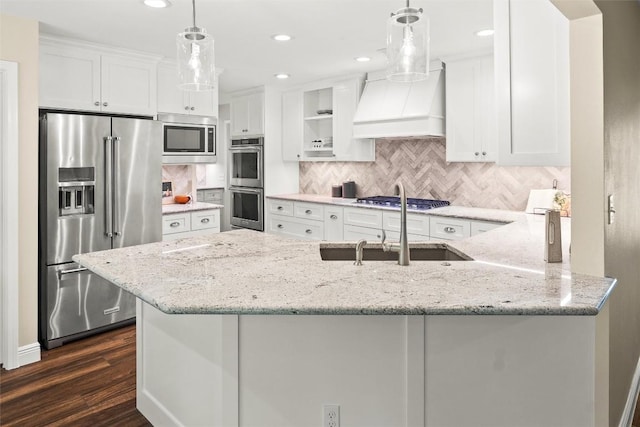 7606 Mesa Dr, Austin, TX 78731 - kitchen featuring appliances with stainless steel finishes, custom exhaust hood, white cabinetry, a peninsula, and light stone countertops