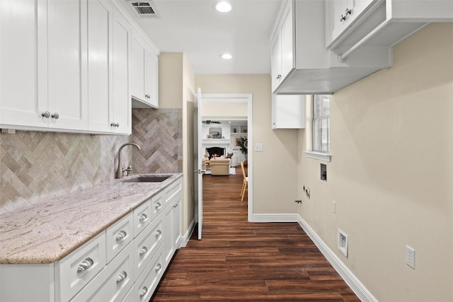 7606 Mesa Dr, Austin, TX 78731 - kitchen featuring dark wood finished floors, light stone countertops, tasteful backsplash, white cabinetry, and recessed lighting