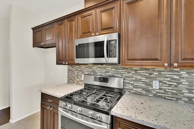 1718 Zydeco Dr, Round Rock, TX 78664 - kitchen with appliances with stainless steel finishes, light stone counters, decorative backsplash, and light tile patterned floors