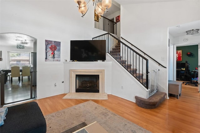 1424 Roxannes Run, Pflugerville, TX 78660 - living room featuring wood finished floors, a chandelier, stairs, a towering ceiling, and arched walkways