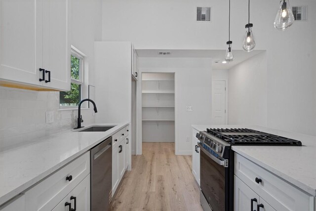 3405 Dunliegh Dr, Austin, TX 78745 - kitchen with stainless steel appliances, light wood-style flooring, light stone counters, white cabinets, and tasteful backsplash