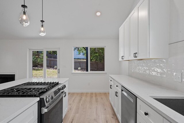3405 Dunliegh Dr, Austin, TX 78745 - kitchen featuring stainless steel appliances, light wood-type flooring, tasteful backsplash, decorative light fixtures, and light stone countertops