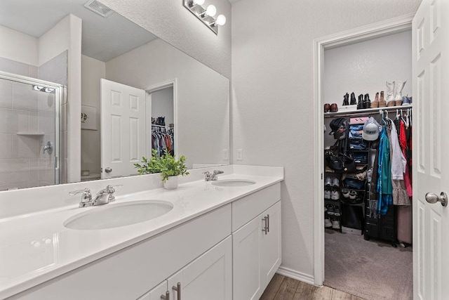 1925 T H Johnson Dr, Taylor, TX 76574 - full bathroom with double vanity, a spacious closet, a stall shower, and wood finished floors