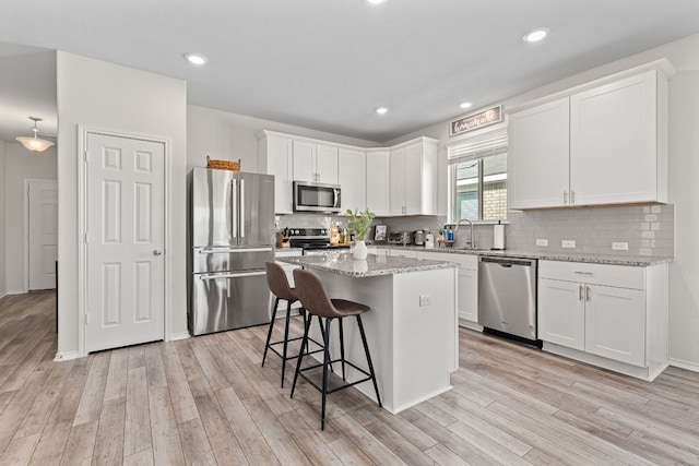 1925 T H Johnson Dr, Taylor, TX 76574 - kitchen with stainless steel appliances, white cabinets, light wood finished floors, a kitchen breakfast bar, and a kitchen island