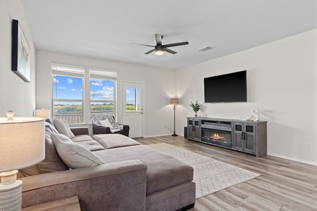 1925 T H Johnson Dr, Taylor, TX 76574 - living room with ceiling fan, light wood-style floors, and a glass covered fireplace