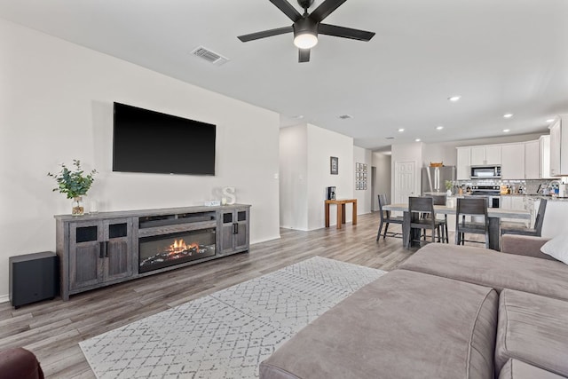 1925 T H Johnson Dr, Taylor, TX 76574 - living room featuring a ceiling fan, light wood finished floors, recessed lighting, and a glass covered fireplace