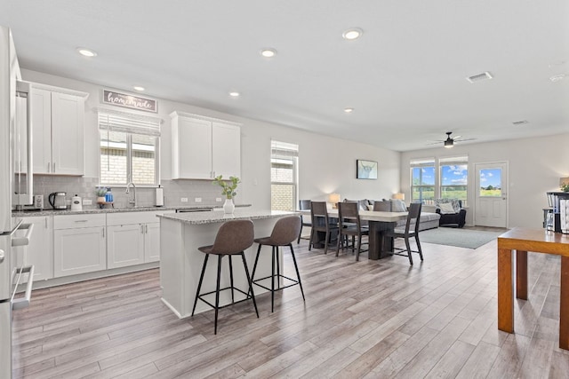 1925 T H Johnson Dr, Taylor, TX 76574 - kitchen with a kitchen island, light wood-type flooring, white cabinets, open floor plan, and recessed lighting
