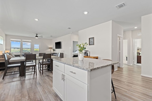1925 T H Johnson Dr, Taylor, TX 76574 - kitchen with open floor plan, light wood-type flooring, ceiling fan, a center island, and light stone counters