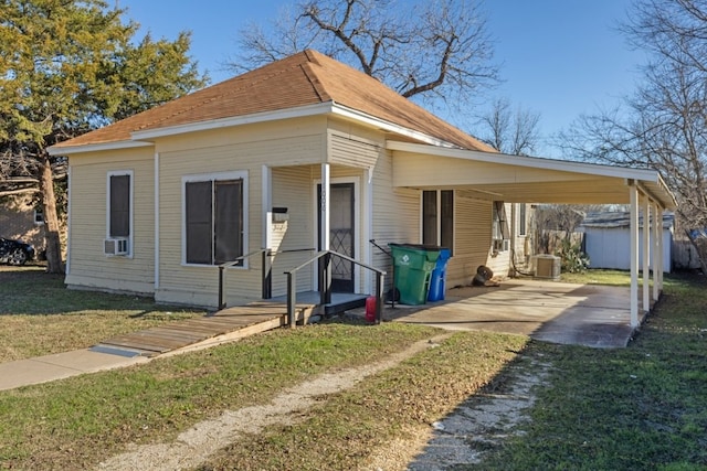 1006 Porter St, Taylor, TX 76574 - view of front of home featuring a front yard, a storage unit, a carport, cooling unit, and roof with shingles